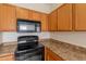 Wooden kitchen cabinets with black microwave and stove and neutral countertops at 2210 N 27Th Pl, Phoenix, AZ 85008