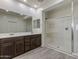 A bright bathroom featuring a dual sink vanity, large mirror, and a glass-enclosed walk-in shower at 23097 E Camina Buena Vis, Queen Creek, AZ 85142