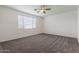 A comfortable bedroom with neutral carpeting, a ceiling fan, and a bright window for natural light at 23097 E Camina Buena Vis, Queen Creek, AZ 85142