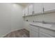 Clean laundry room features white cabinets, a utility sink, and wood-look floors at 23097 E Camina Buena Vis, Queen Creek, AZ 85142