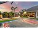 Serene backyard featuring a basketball court, pool, lush greenery, fire pit, and cozy lounge areas at dusk at 23465 S 202Nd St, Queen Creek, AZ 85142