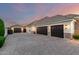 Elegant home exterior with multiple garage doors, brick accents, paved driveway, and manicured landscaping at 23465 S 202Nd St, Queen Creek, AZ 85142