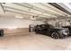Well-lit garage with a modern black SUV parked inside, stainless steel refrigerator, and tile accent wall at 23465 S 202Nd St, Queen Creek, AZ 85142