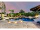Inviting pool with waterfall, spa, lush landscaping, and an illuminated travertine patio at dusk at 23465 S 202Nd St, Queen Creek, AZ 85142