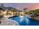 Beautiful backyard featuring a pool with rock waterfall, spa, sports court and outdoor seating at dusk at 23465 S 202Nd St, Queen Creek, AZ 85142