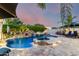 Stunning backyard pool with a rock waterfall, spa, palm trees, and elegant patio lighting creating a tranquil oasis at 23465 S 202Nd St, Queen Creek, AZ 85142