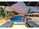Inviting backyard pool with a waterfall, spa, lounge chairs, and lush tropical landscaping under a colorful sky at 23465 S 202Nd St, Queen Creek, AZ 85142