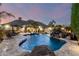 Stunning backyard featuring a pool with rock waterfall, spa, outdoor seating, and lush palm trees at 23465 S 202Nd St, Queen Creek, AZ 85142