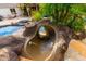 Outdoor rock-lined waterslide leading into a beautiful pool and spa surrounded by lush landscaping at 23465 S 202Nd St, Queen Creek, AZ 85142