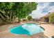 Secluded backyard retreat featuring a freeform pool, covered patio, and lush landscaping, offering privacy and relaxation at 2405 E Lynwood Cir, Mesa, AZ 85213