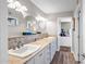 Bathroom featuring dual vanities with white cabinets and access to a room at 2405 E Lynwood Cir, Mesa, AZ 85213