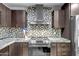 Updated kitchen showcasing stainless steel appliances, dark wood cabinetry, and mosaic tile at 2405 E Lynwood Cir, Mesa, AZ 85213