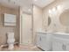 Bright bathroom with white cabinets, dual sinks, a shower, toilet, and light wood-look floors at 3514 E Desert Willow Rd, Phoenix, AZ 85044