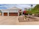 A white house with a large driveway, three-car garage, and colorful landscaping at 3514 E Desert Willow Rd, Phoenix, AZ 85044