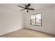 Bright bedroom featuring neutral carpet, ceiling fan, and a front-facing window at 3619 E Marmora St, Phoenix, AZ 85032