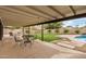Covered patio with outdoor seating overlooks a manicured lawn and sparkling swimming pool at 3619 E Marmora St, Phoenix, AZ 85032