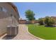 Backyard with gravel landscaping, artificial grass, and shrubbery next to AC unit at 42347 W Bunker Dr, Maricopa, AZ 85138