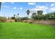 A large, green backyard is enclosed by a block wall with flowering bushes and various desert plants at 6725 E Kings Ave, Scottsdale, AZ 85254