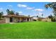A grassy backyard with a covered patio featuring stylish furniture and a view of the home's rear facade at 6725 E Kings Ave, Scottsdale, AZ 85254