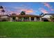 An expansive backyard features a covered patio area adjacent to a lush green lawn and desert plants at 6725 E Kings Ave, Scottsdale, AZ 85254