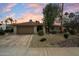 The front exterior of a single-story home with tan brick, a two-car garage, and desert landscaping at dusk at 6725 E Kings Ave, Scottsdale, AZ 85254