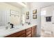 Bathroom with a double sink vanity, large mirror, wood cabinets, and a view into the toilet and shower area at 9622 S 46Th Ln, Laveen, AZ 85339