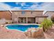 Backyard view showcasing a refreshing pool with rock features and covered patio, perfect for outdoor relaxation at 9622 S 46Th Ln, Laveen, AZ 85339