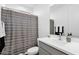 Well-lit bathroom with a shower featuring a grey and white textured curtain and an elegant sink at 11334 S 52Nd Ln, Laveen, AZ 85339