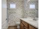 This is a bathroom with a white toilet, wood-colored cabinets, and floral wallpaper at 1143 S Annie Ln, Gilbert, AZ 85296