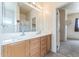 Bathroom with double sinks, wood cabinets, large mirror, and an open doorway to another room at 120 N Pottebaum Rd, Casa Grande, AZ 85122