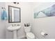 Charming powder room featuring a pedestal sink, decorative mirror, and beach-themed artwork at 13353 W Gloria Ln, Peoria, AZ 85383