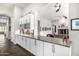 An open concept kitchen featuring white cabinets, stone countertops, and view into the living room at 14523 E Charter Oak Dr, Scottsdale, AZ 85259