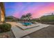 Inviting pool and spa with stone surround, set against a backdrop of a beautiful sunset sky at 14523 E Charter Oak Dr, Scottsdale, AZ 85259