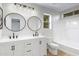 Bathroom with double vanity, round mirrors, modern fixtures, and tub shower with tile surround at 1563 S Longspur Ln, Gilbert, AZ 85296