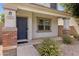 Home's covered porch with stylish brick accents, dark blue door, desert landscaping, and neutral stucco at 1563 S Longspur Ln, Gilbert, AZ 85296
