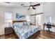 Bedroom with a large bed, wood floors, ceiling fan, and a barn door to bathroom at 15743 N 165Th Ln, Surprise, AZ 85388