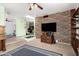 Spacious living room featuring brick accent wall, mounted TV, and built in shelving at 1715 S Cholla St, Mesa, AZ 85202