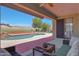 Relaxing covered patio with comfortable seating, offering scenic views of the pool and landscaped backyard at 18550 W Mcneil St, Goodyear, AZ 85338