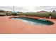 A kidney-shaped pool with seating, lush landscaping and a privacy wall at 18550 W Mcneil St, Goodyear, AZ 85338