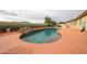 Kidney-shaped pool features a faux rock grotto and orange concrete deck and privacy walls at 18550 W Mcneil St, Goodyear, AZ 85338