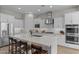 Bright, all-white kitchen featuring a large island with seating, stainless steel appliances, and modern finishes at 21132 W Windsor Ave, Buckeye, AZ 85396