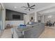 Comfortable living room with a large gray sectional, TV, ceiling fan, and seamlessly connected to other living areas at 21132 W Windsor Ave, Buckeye, AZ 85396