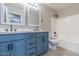 Well-lit bathroom featuring double sinks, updated fixtures and blue cabinets and shower/tub combo with white tiled enclosure at 29891 N Desert Angel Dr, San Tan Valley, AZ 85143