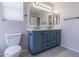 Well-lit bathroom featuring double sinks, updated fixtures and blue cabinets and a large mirror at 29891 N Desert Angel Dr, San Tan Valley, AZ 85143