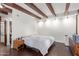 Comfortable bedroom features exposed beams, wood floors, neutral paint, and ample natural lighting at 301 W Royal Palm Rd, Phoenix, AZ 85021
