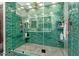Modern glass shower featuring green tile, built-in shelves, and pebble flooring at 301 W Royal Palm Rd, Phoenix, AZ 85021