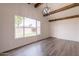 Living room with new light floors and wooden beams on the ceiling facing a large window at 3620 E Ludlow Dr, Phoenix, AZ 85032