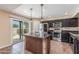A kitchen featuring stainless steel appliances, a granite island with pendant lighting, and access to the outdoor pool area at 4114 E Muirwood Dr, Phoenix, AZ 85048