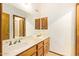 Bathroom with double marble sinks, wood cabinets, as well as a large mirror at 4922 W Fallen Leaf Ln, Glendale, AZ 85310