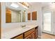 Bathroom with a marble sink and wood cabinets, as well as a large mirror and a glass door leading outside at 4922 W Fallen Leaf Ln, Glendale, AZ 85310